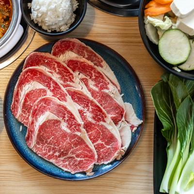 Sliced meat on a plate, salad leaves, white rice in a small cup.