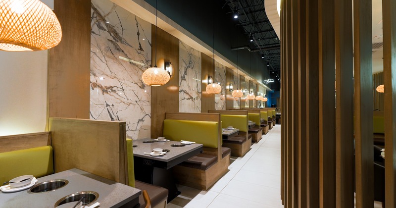 Modern interior dining area with lined up tables equipped with built-in hot pot burners