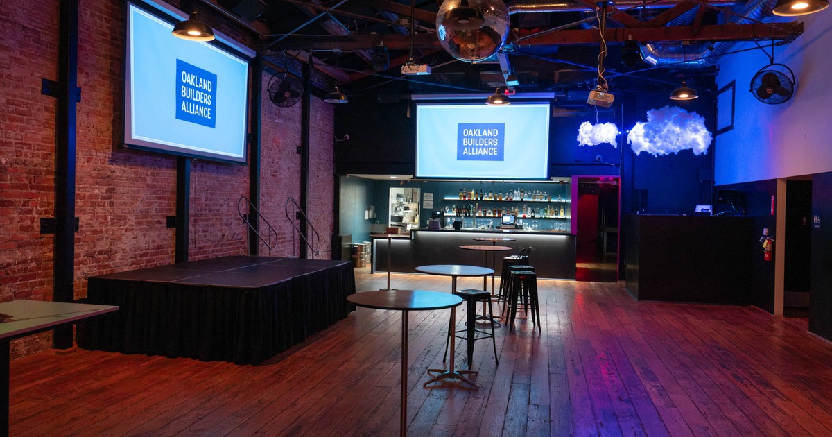 Interior, a stage on the left with a bar tables and chairs in front of it