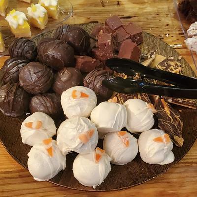 A platter with an assortment of chocolate truffles, white candies, and fudge squares.