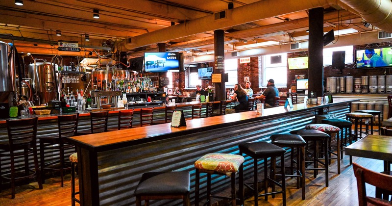 Brewpub interior with guests at the bar and brewing equipment in the background