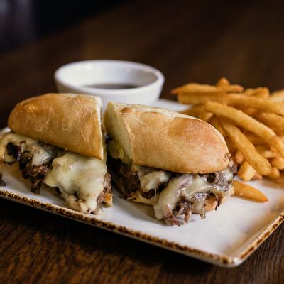 French dip sandwich with cheese, served with fries and beef broth.
