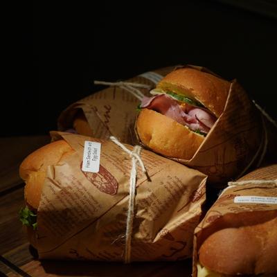 Several sandwiches wrapped in brown paper and tied with twine.