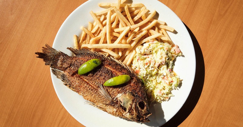 Fries fish, served with salad, rice, and beans