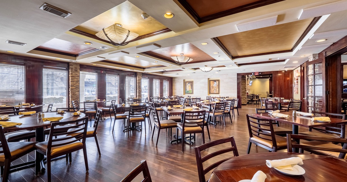 Spacious restaurant interior with wooden tables, chairs, and large windows