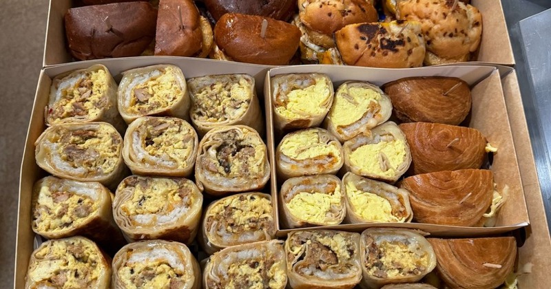 Catering trays with breakfast burrito and assorted sandwiches