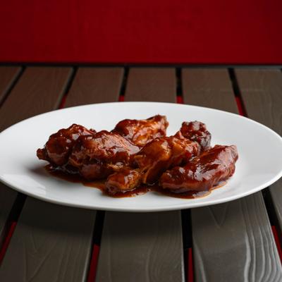 BBQ Chicken Wings on a white plate, served on a wooden table.