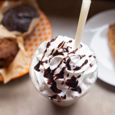 Frappe topped with whipped cream and chocolate sauce, alongside food items.