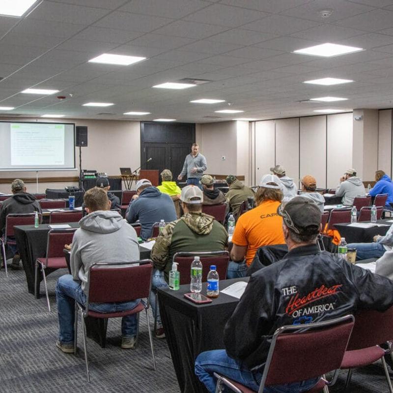 Lots of people sitting in a large audience hall, listening to a speaker.