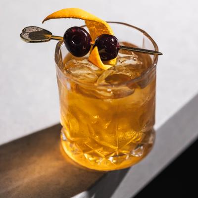 Old Fashioned cocktail garnished with cherries and a orange peel.