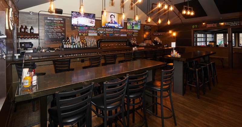 Interior, long wooden tables and chairs, bar in the back