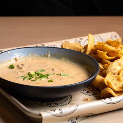 Rotel Dip, with beef, tomatoes, and green chile cheese, served with corn chips.