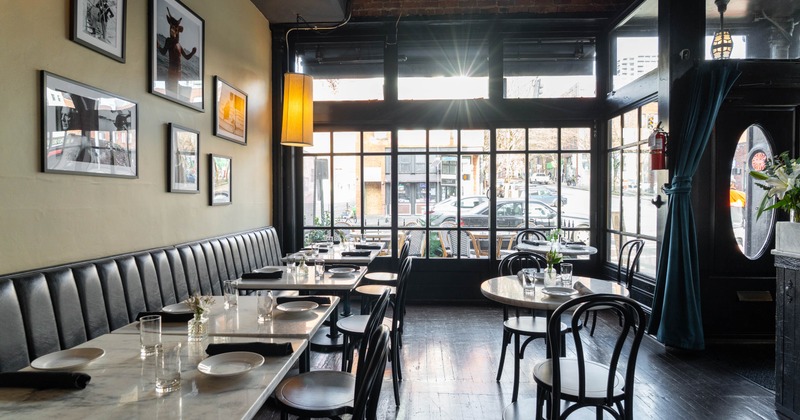 Interior of a restaurant with marble tables, black chairs, and large windows