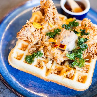 fried chicken and walnut butter on waffle on blue plate