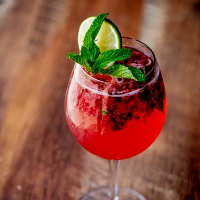 Pomegranate juice soda garnished with lime wheel and a mint spring.