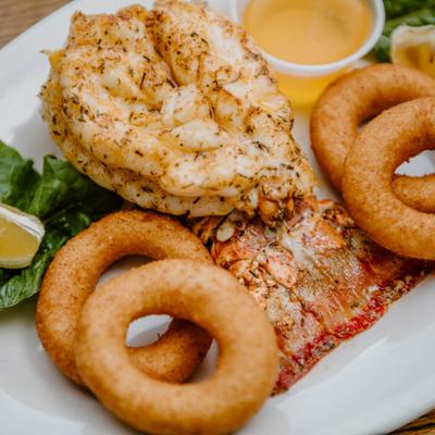Lobster Tail served with onion rings, lemon wedge and melted butter.