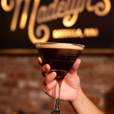 A hand holding an espresso martini.