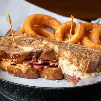 Reuben sandwich served with onion rings.