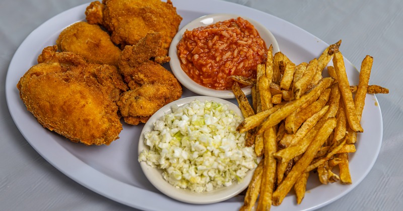 Fried chicken with coleslaw, rice in tomato sauce, and crispy fries
