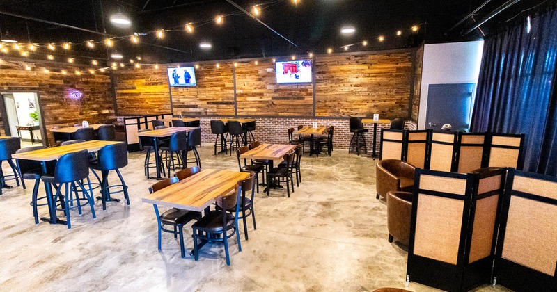 Interior, open space seating area, high and regular tables with chairs, concrete flooring