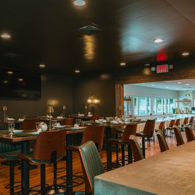 Elegant dining room with set tables and green chairs.