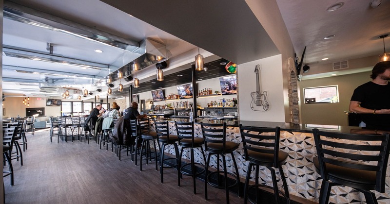 Interior, a bar area with bar stools and customers in the back