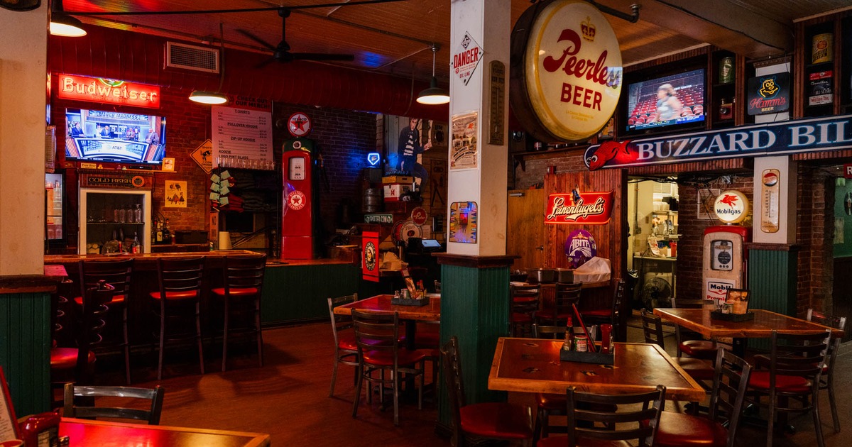 Interior, seating area, tables with chairs, various neon drink signs, miscellaneous decoration