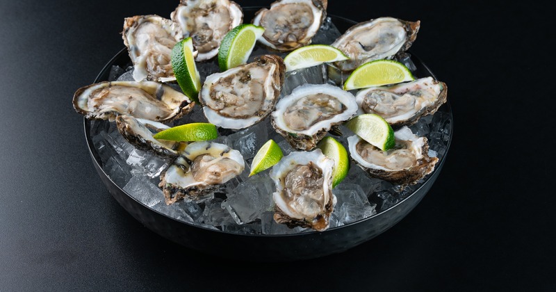 Fresh oysters served on ice with lime wedges
