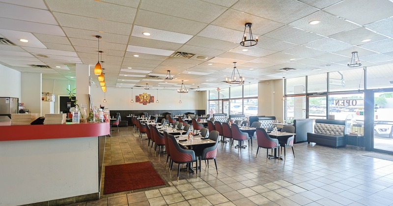 Interior of a modern restaurant with black and red chairs, black tables, tiled floor