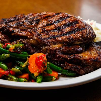 Grilled steak with green beans and carrots on a plate.