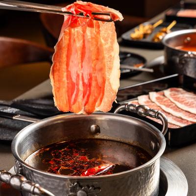 Thinly sliced beef being dipped into a simmering hot pot broth.