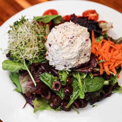 Tuna salad platter, with mixed greens, sprouts, black olives, cherry tomatoes, and carrots.