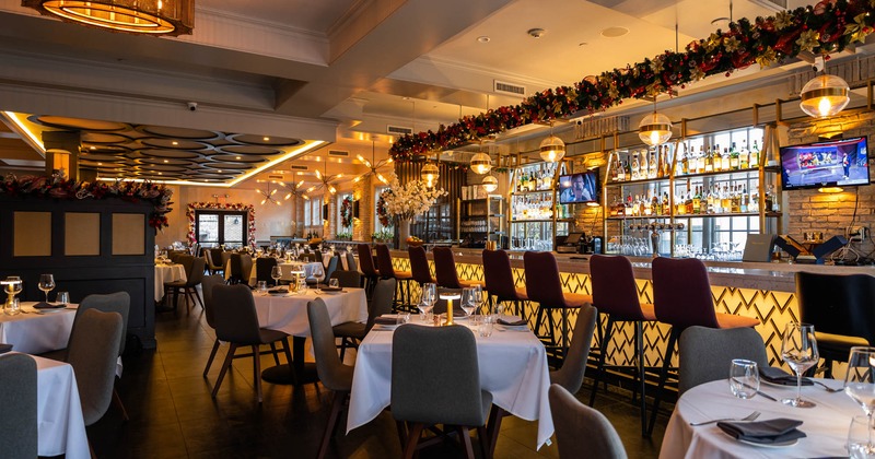 Interior, tables and chairs ready for guests, bar with bar stools on the right