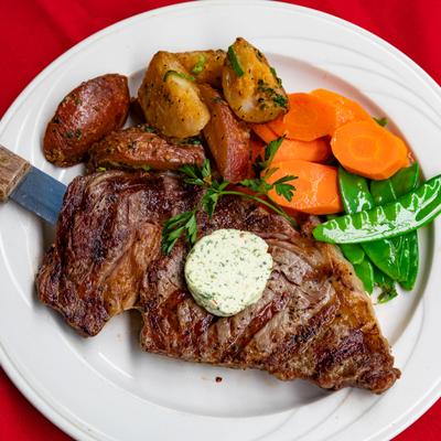 Grilled ribeye steak serve with roasted potatoes, carrots, and green beans.