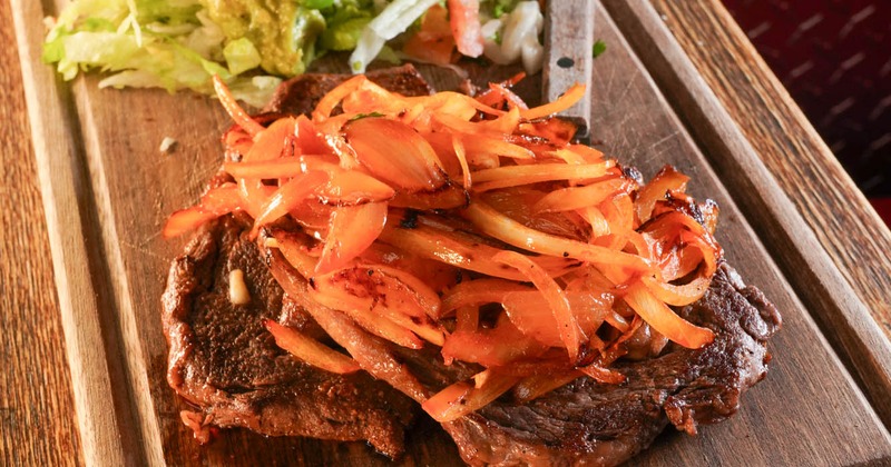 Grilled ribeye with grilled onions, served with guacamole and salad