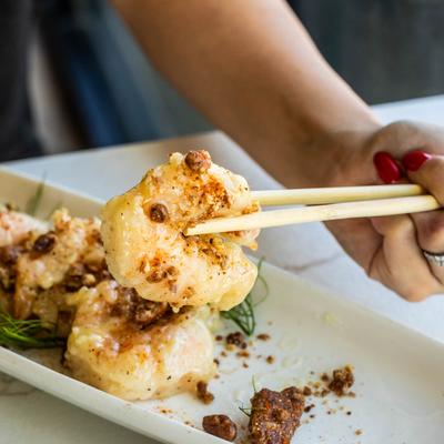 Honey Glazed Shrimp plate, a person holds a shrimp with chopsticks, close up