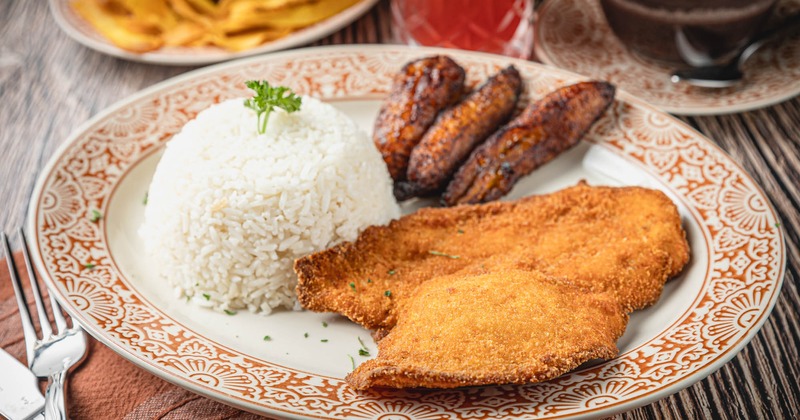 Breaded and fried chicken, with fried plantains, and rice