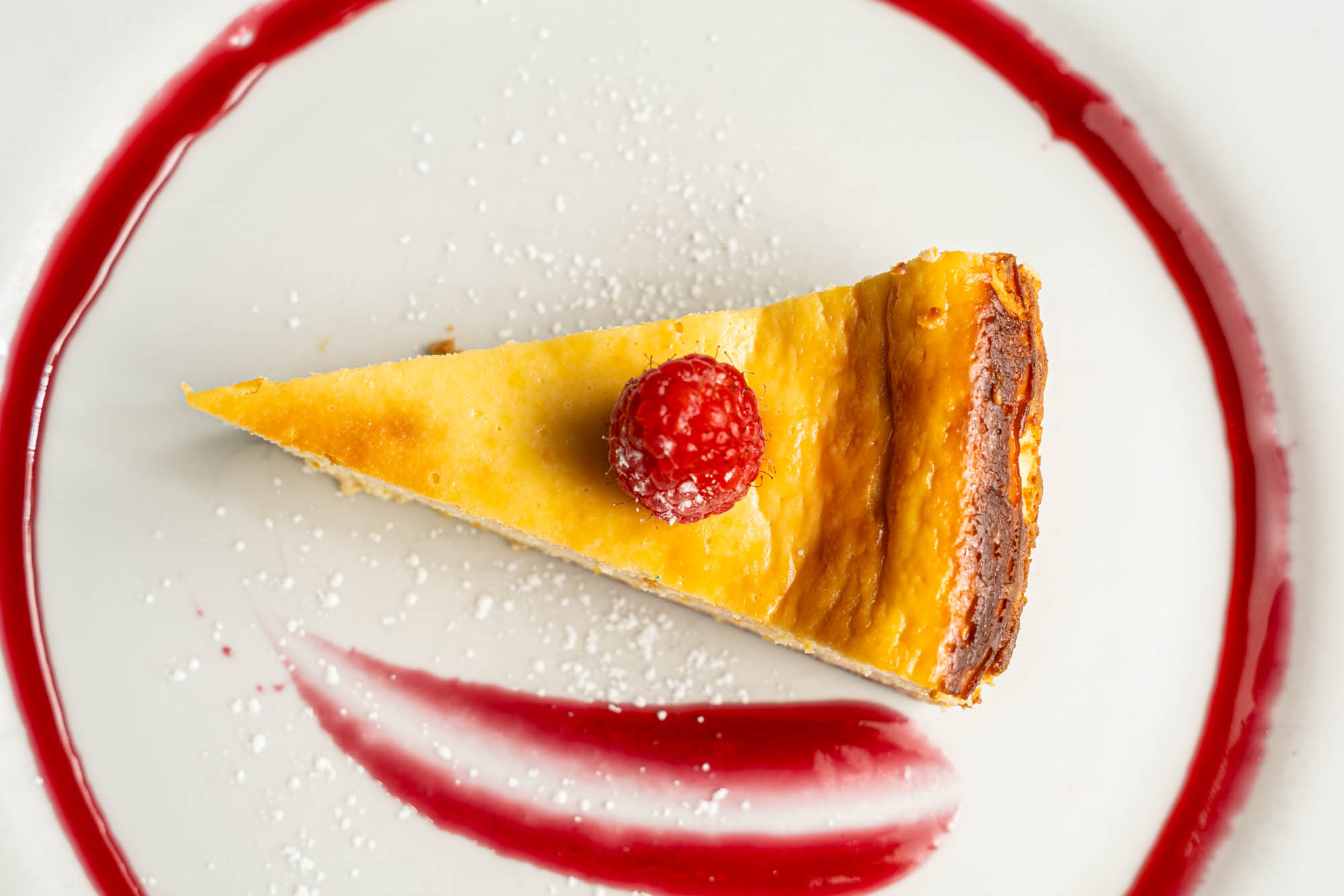 Slice of cheesecake garnished with a raspberry