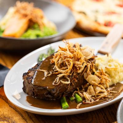 Steak topped with brown gravy and crispy onions, served with mashed potatoes and asparagus.