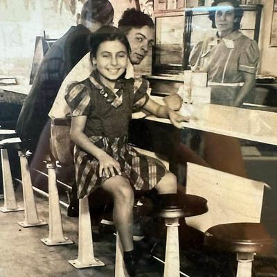 Vintage diner photo showing a smiling child sitting at a counter.