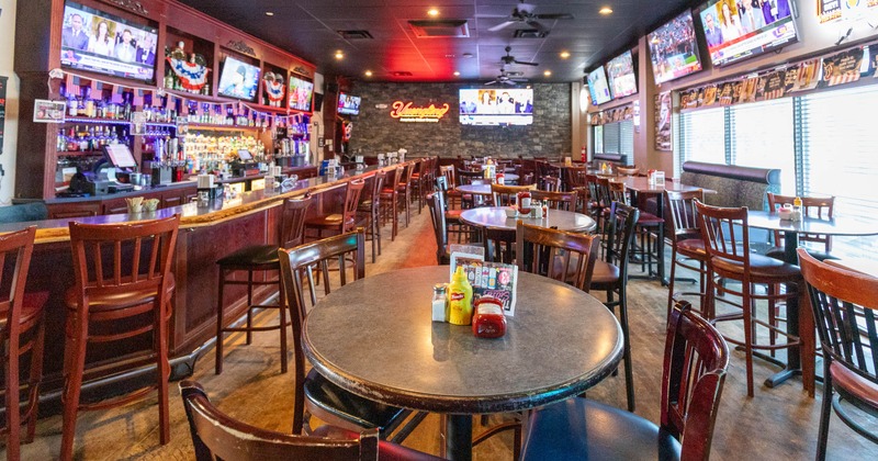 A restaurant interior with a long bar, multiple dining tables