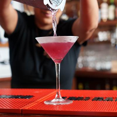 Bartender straining a cocktail into a Martini glass.