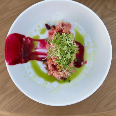 Tuna tartare servced with sauces on the plate and garnished with microgreens.