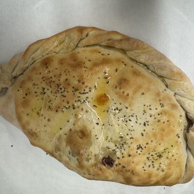 Freshly baked calzone topped with olive oil and spices.