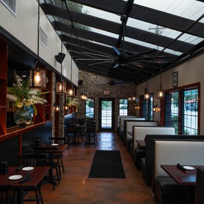 Restaurant interior with booth seating, hanging lights, and rood windows.