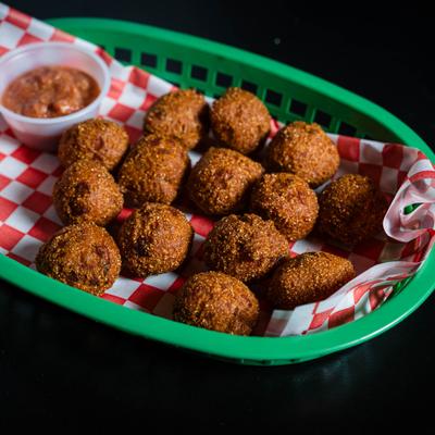 Hash pappies served with dipping sauce in a green basket.