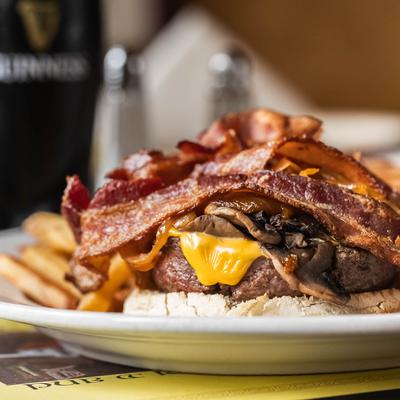 Cheeseburger with bacon, mushrooms, and fries on a plate.
