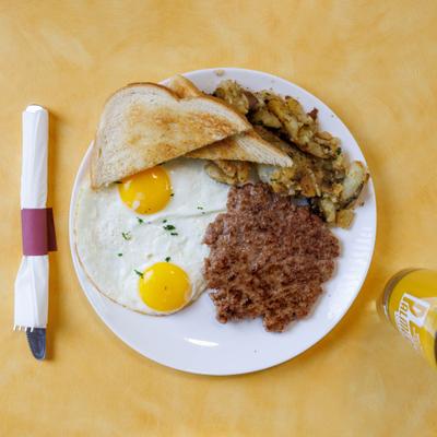 Sausage patty with sunny side up eggs, potatoes, and toast.