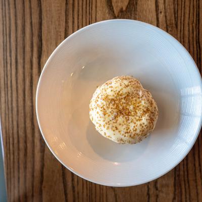 A creme brulee donut served on a white plate atop a wooden table.