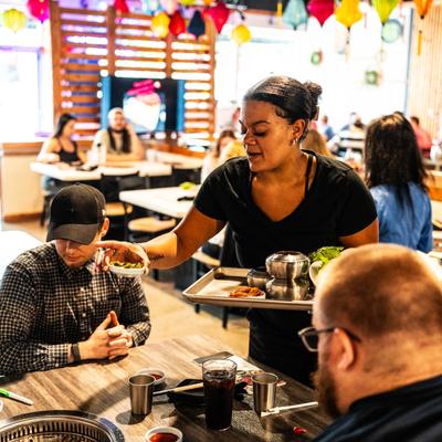 A server delivers small side dishes to customers at DZO Korean BBQ.